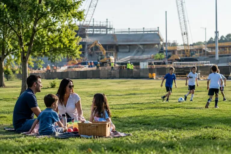 Fans walking near apartment buildings, park paths, and a stadium entrance